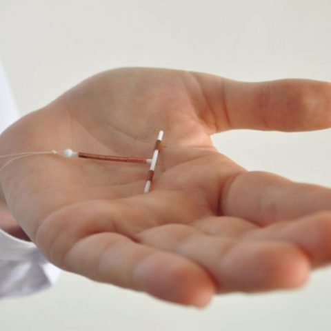 A doctor holds an IUD in their palm